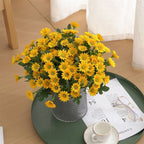 Bouquet of yellow flowers in a vase on a green tray with a newspaper and glasses.