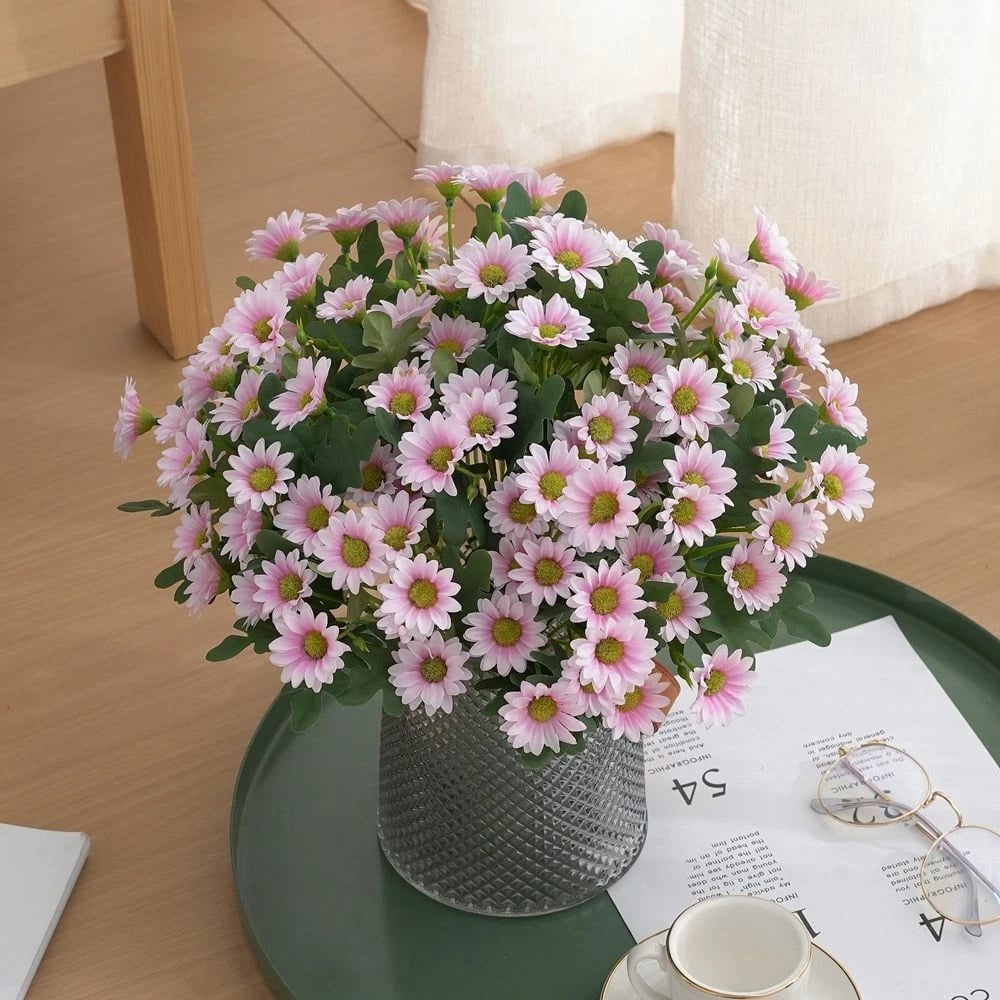 Bouquet of pink flowers in a vase on a table with a magazine underneath