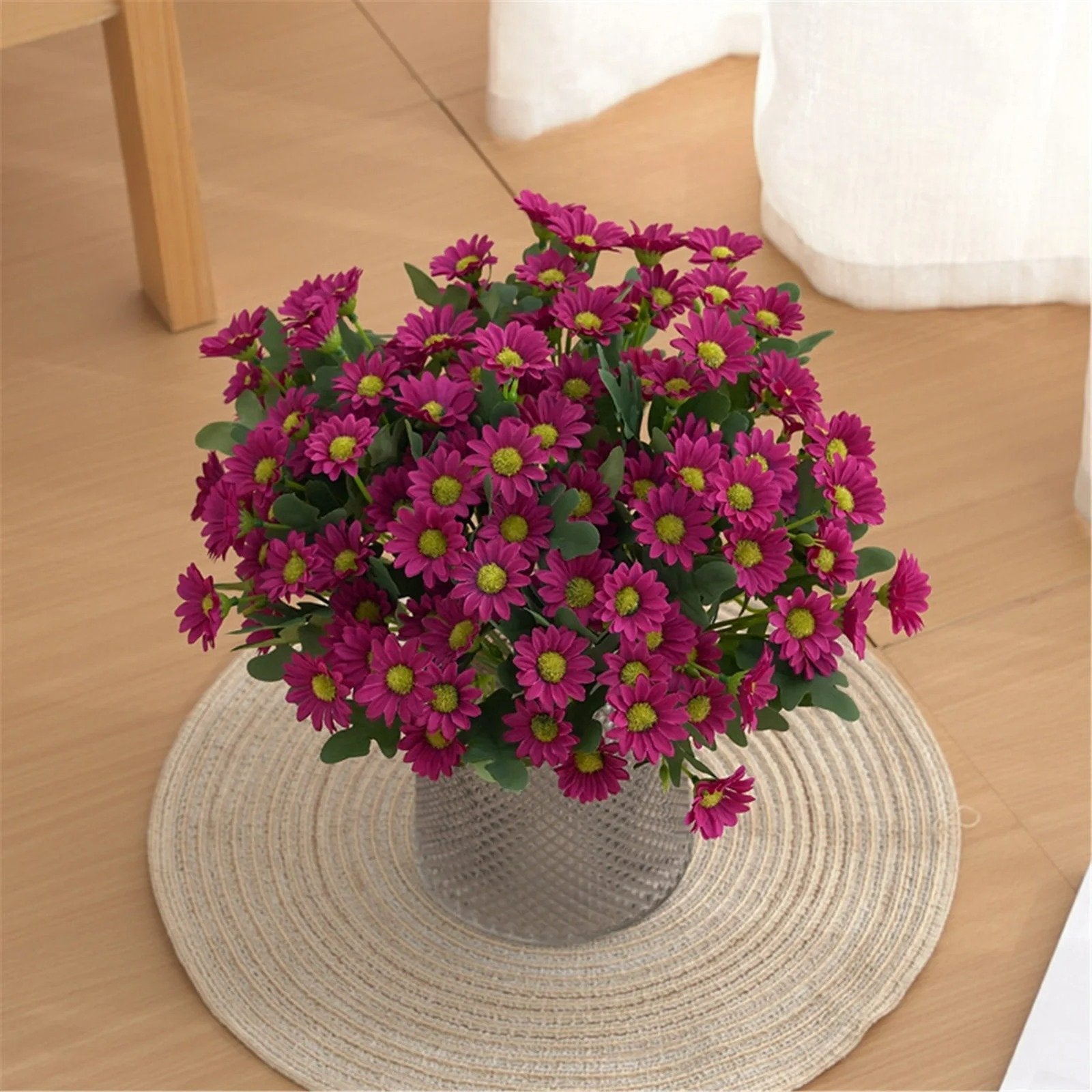 Bouquet of purple flowers in a vase on a woven placemat with a wooden surface background