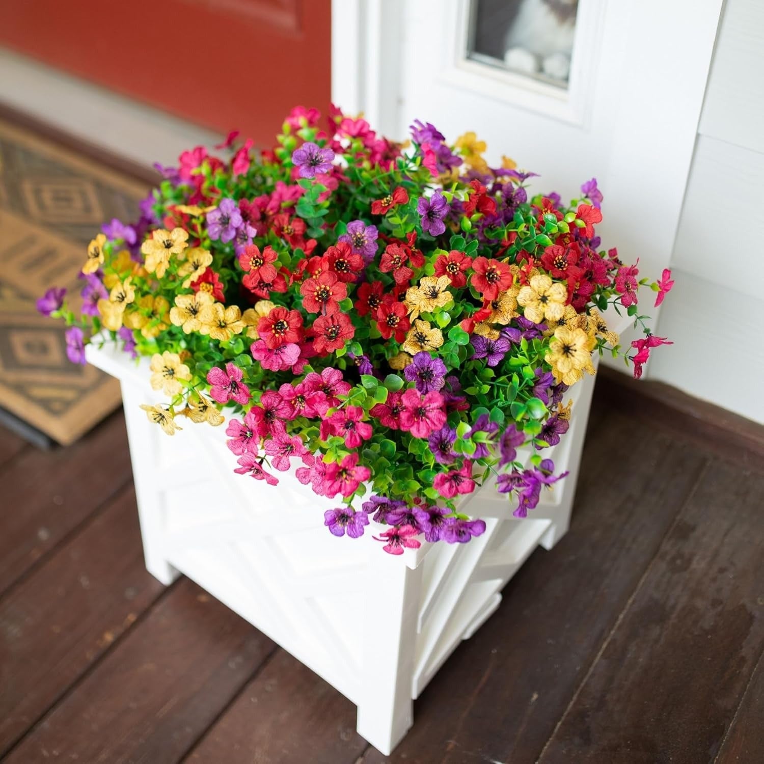 Colorful flowers in a white planter on a wooden deck