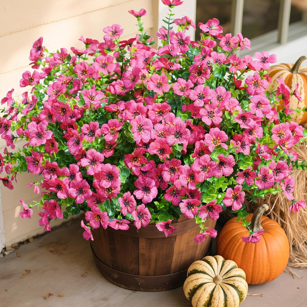 Potted plant with pink flowers and pumpkins on a surface