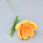 Crocheted yellow flower and green leaf on a light gray background