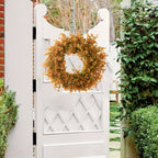Decorative wreath on a white garden gate with greenery around