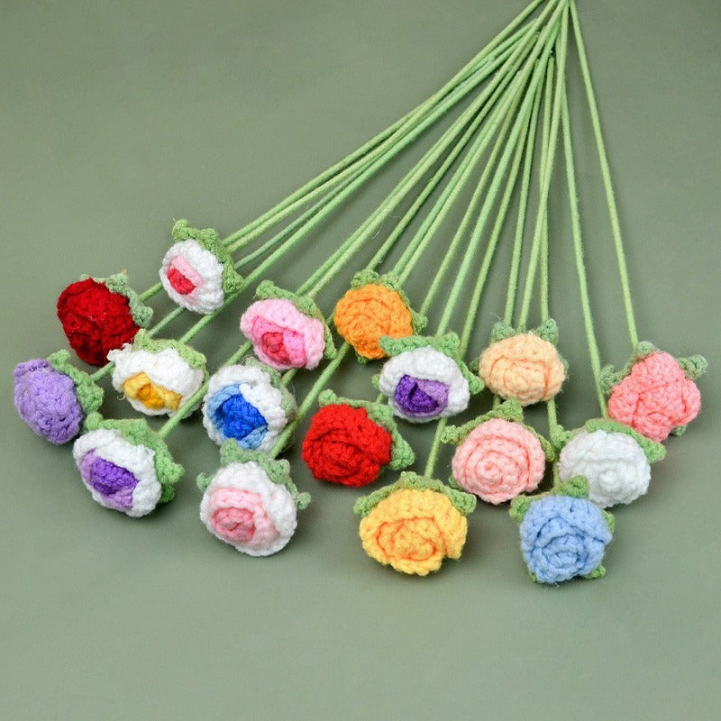 Colorful crocheted flowers on green stems against a green background