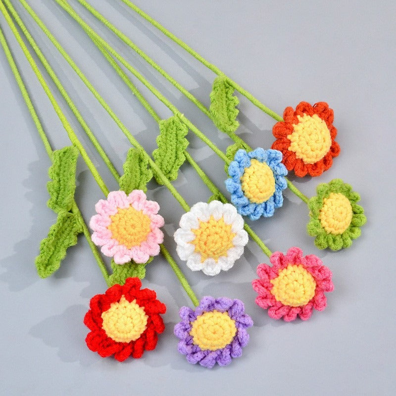 Colorful crocheted flowers on green stems against a gray background