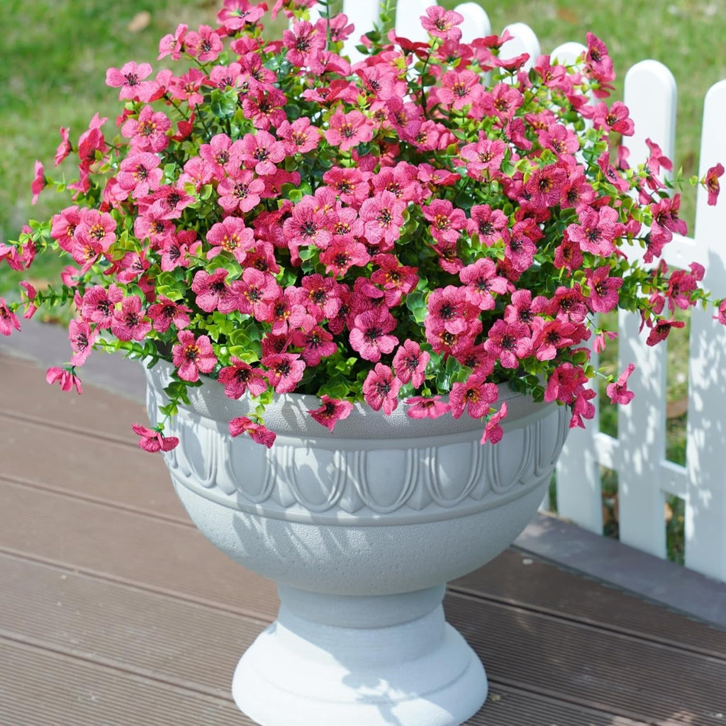 White urn planter with pink flowers on a wooden deck