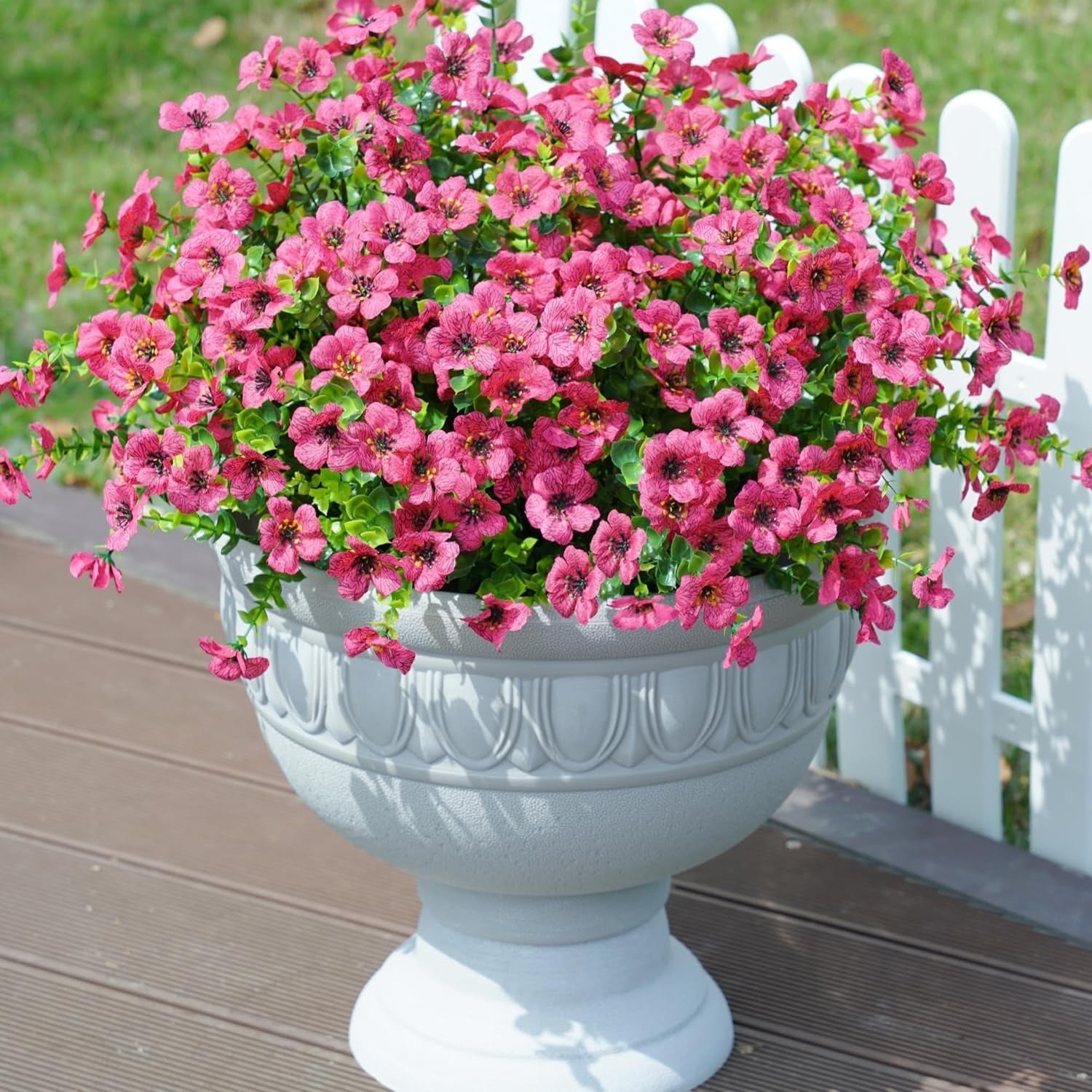 White urn planter with pink flowers on a wooden deck