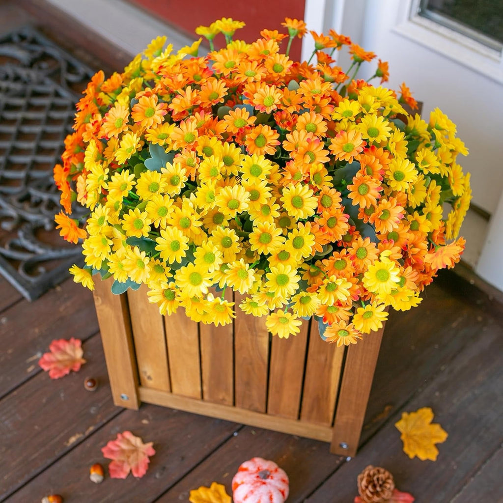 Bouquet of yellow and orange flowers in a wooden planter on a wooden deck.