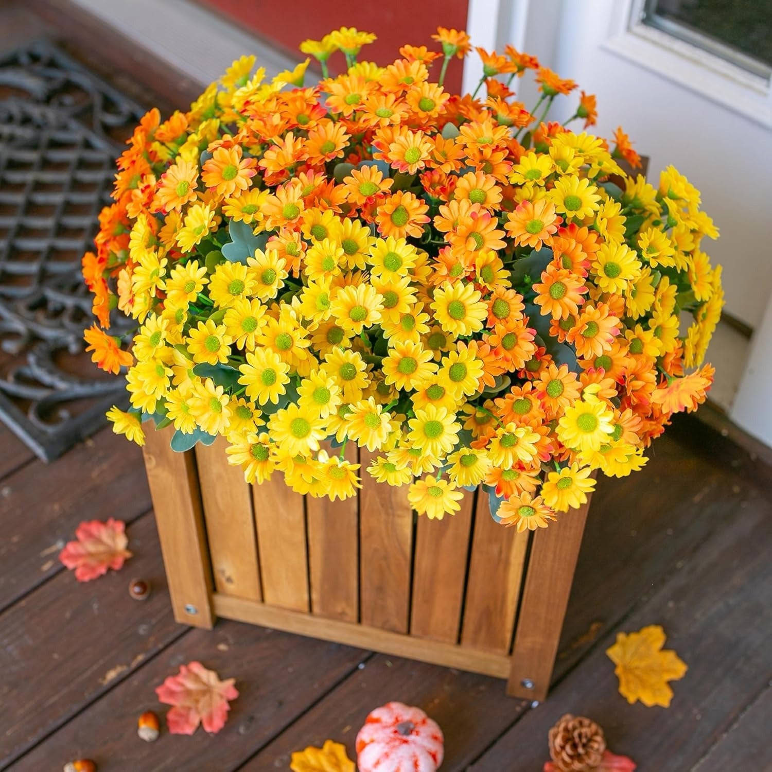Bouquet of yellow and orange flowers in a wooden planter on a wooden deck.