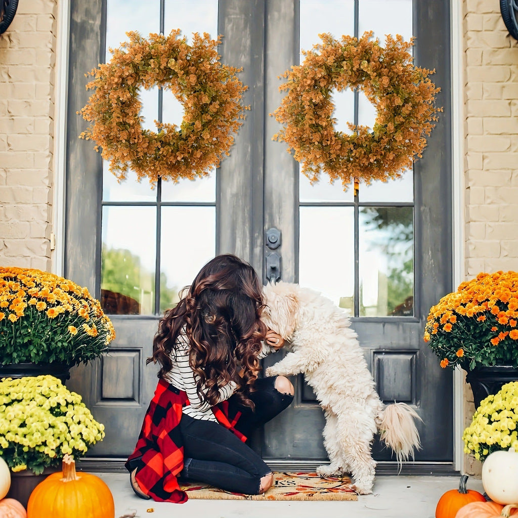 Woman with a dog sitting on a porch decorated for Halloween with wreaths and pumpkins.