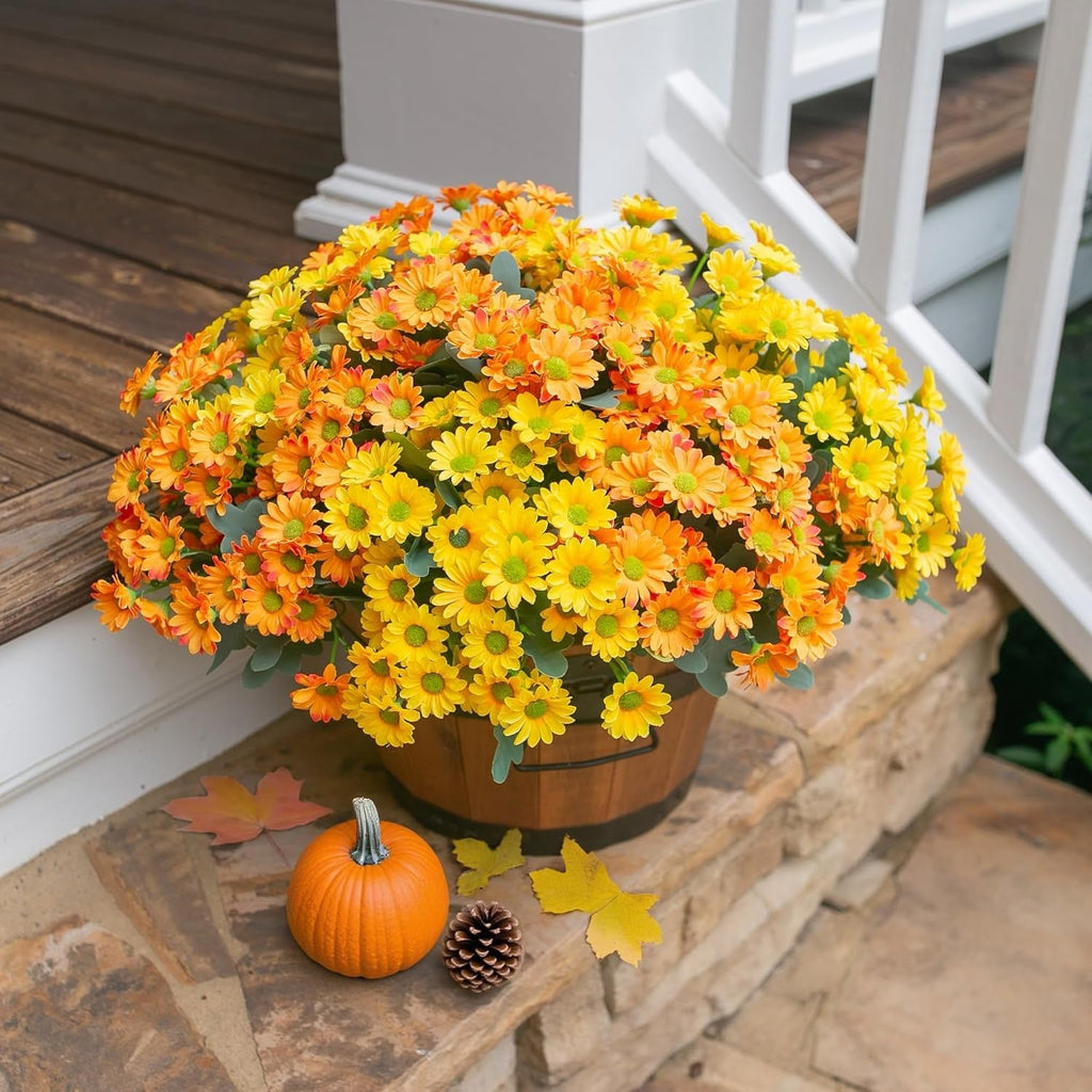 Potted autumnal flower arrangement with pumpkins and leaves on a stone ledge.