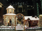 Decorative Christmas scene with a gazebo and gingerbread house in an urban setting.