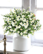 White vase with artificial flowers on a windowsill