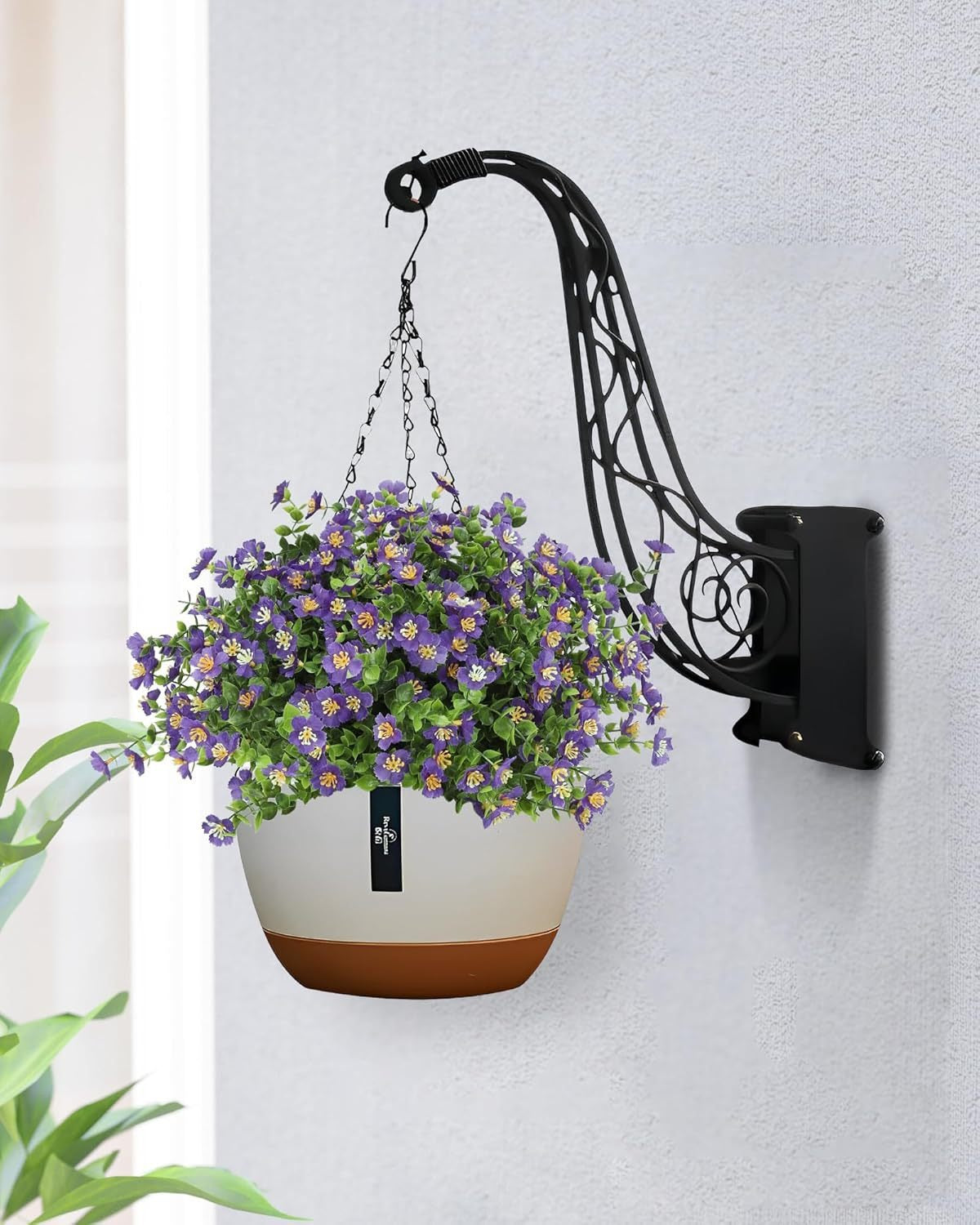 Wall-mounted plant holder with a hanging planter on a light gray wall.