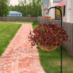 Hanging basket with purple flowers on a metal stand next to a brick pathway in a residential area.