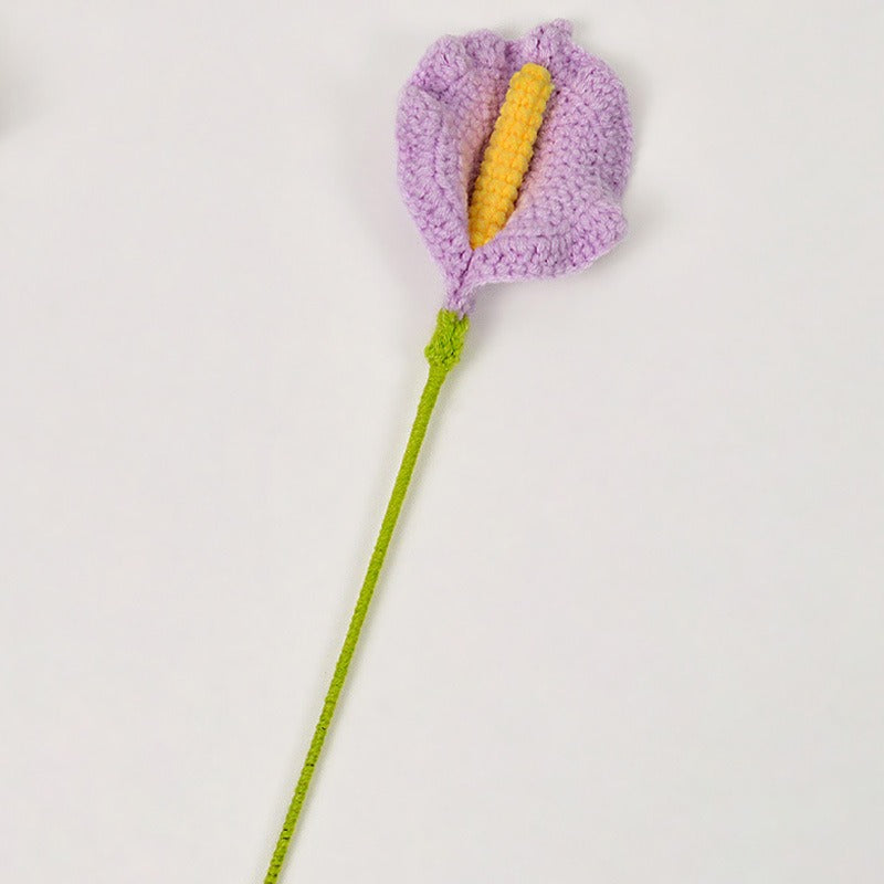 Crocheted flower with purple petals and yellow center on a white background