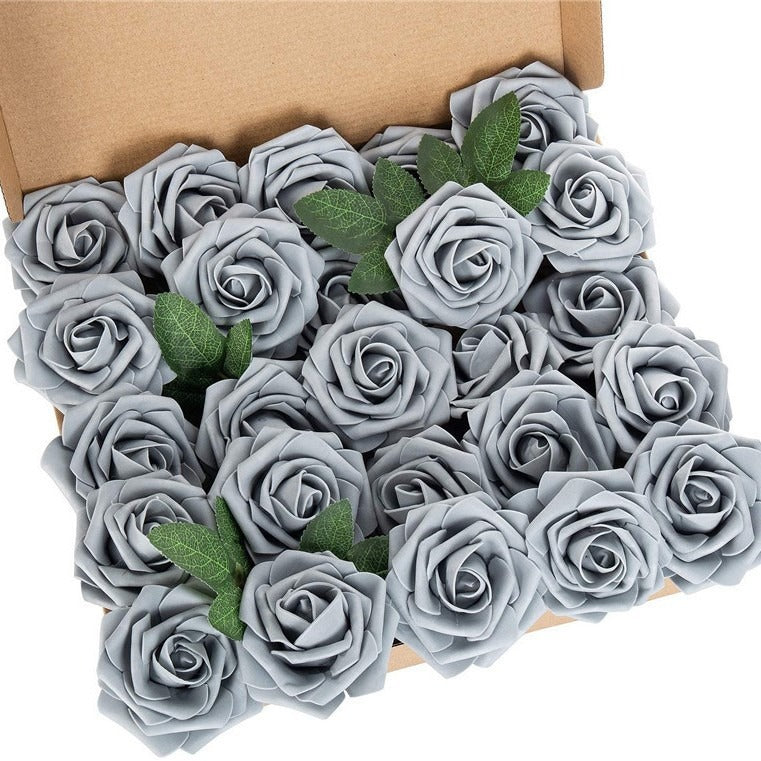 Box of gray artificial roses with green leaves on a white background