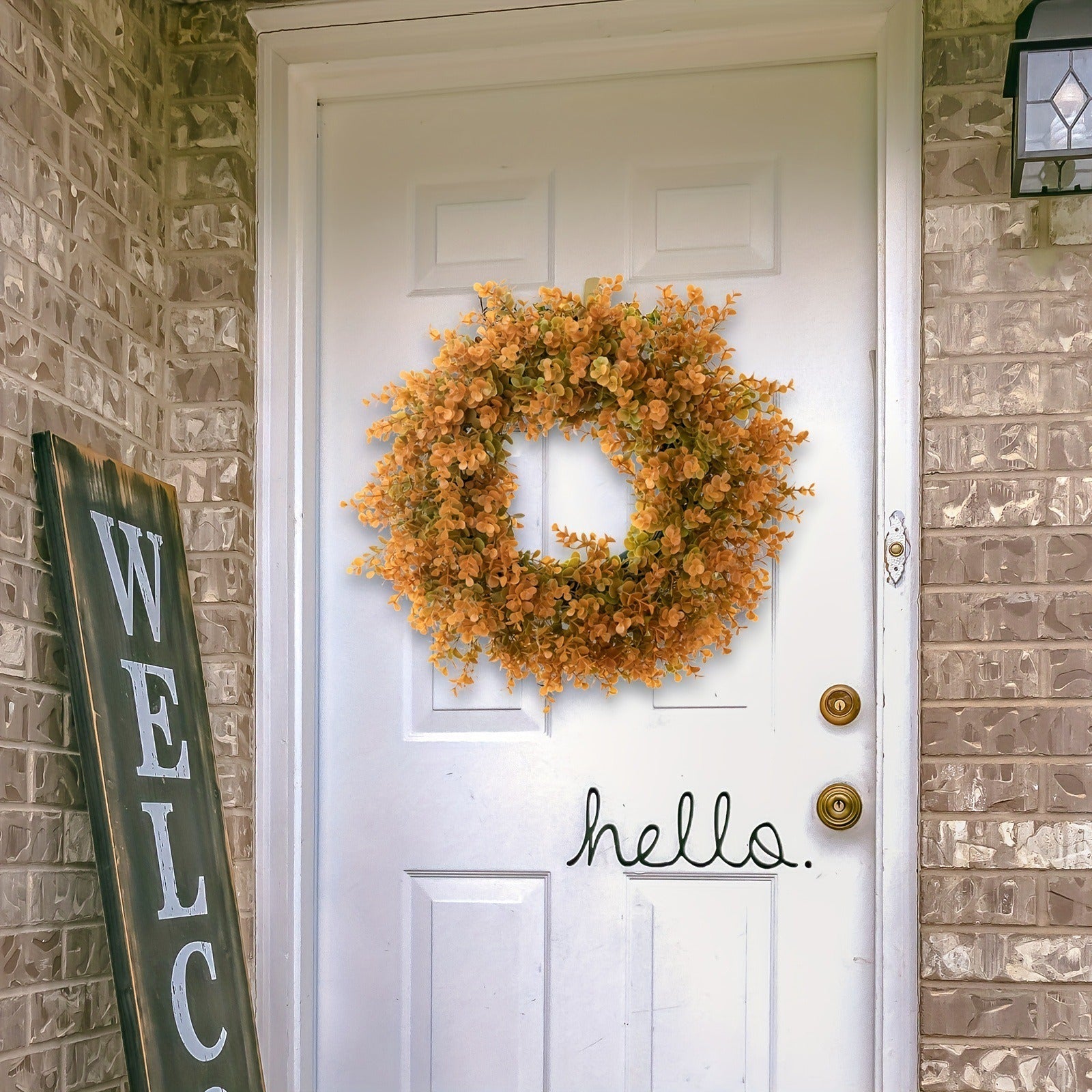 White door with a wreath and 'hello' sign, flanked by brick walls.