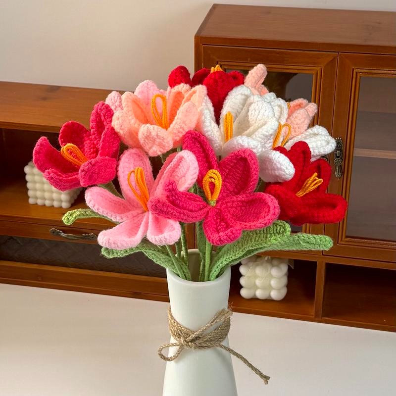 Knitted flowers in a vase on a wooden shelf