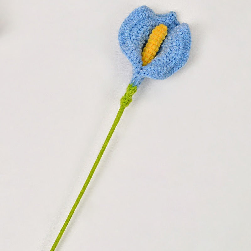 Crocheted blue flower with a yellow center on a white background