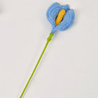 Crocheted blue flower with a yellow center on a white background