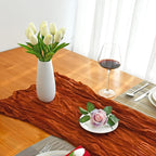 Dining table set with a vase of white tulips, a glass of red wine, and a small dish with a pink rose.