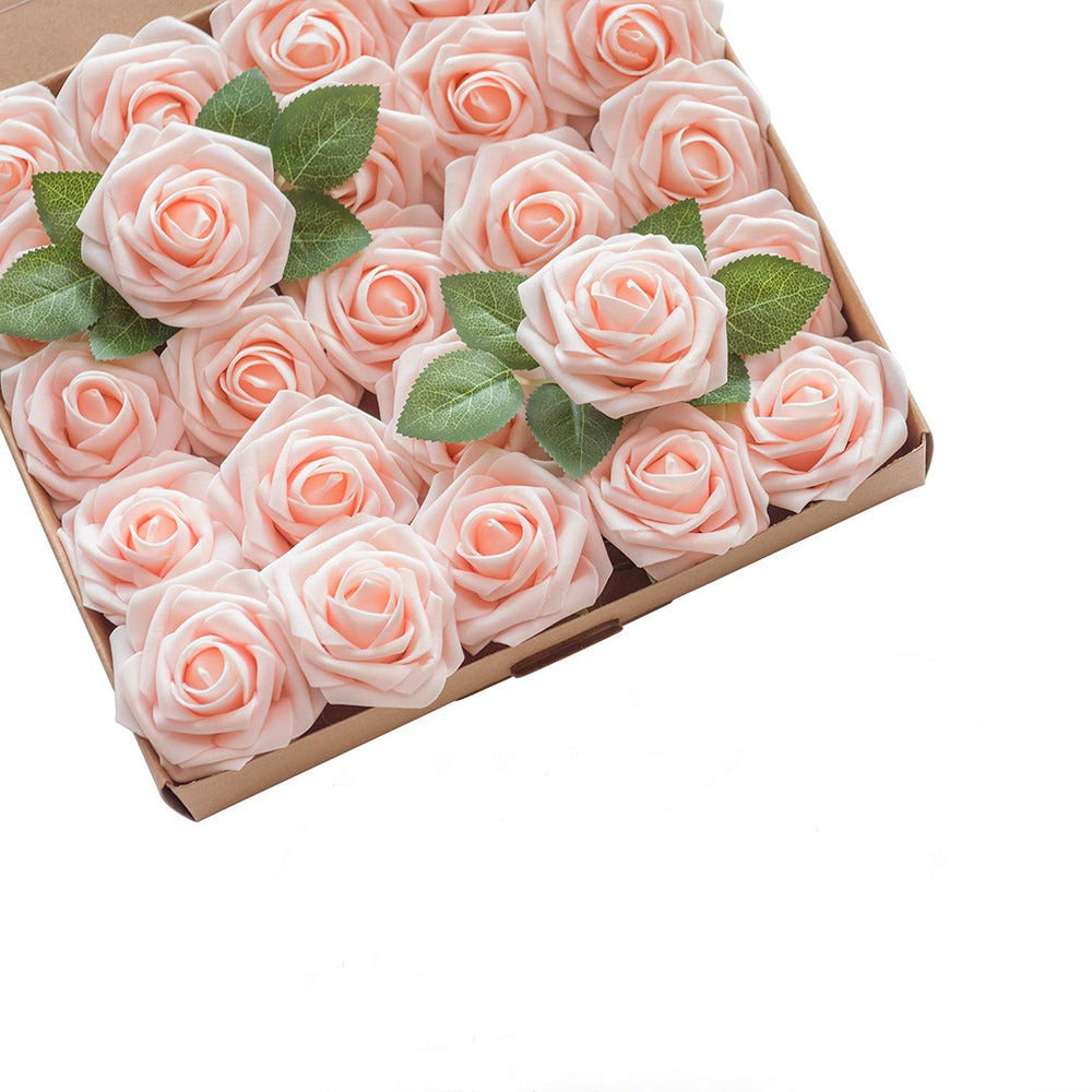 Box of pink artificial roses with green leaves on a white background