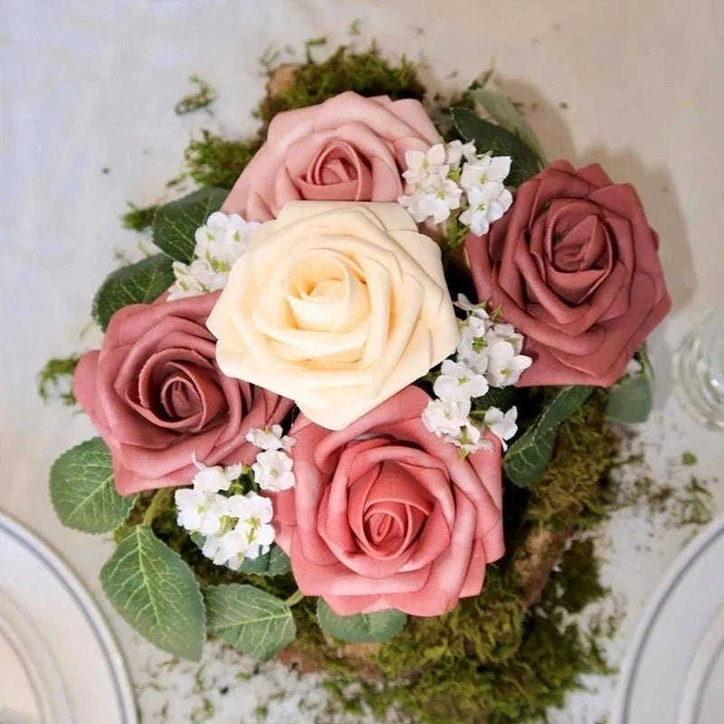 Bouquet of pink and white roses with green leaves on a textured surface
