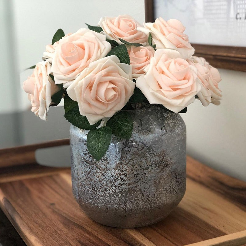 Decorative vase with pink roses on a wooden surface