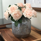 Decorative vase with pink roses on a wooden surface