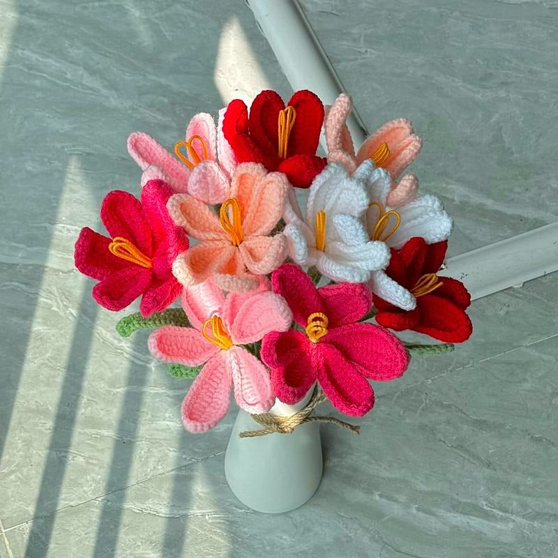 Colorful knitted flowers in a white vase on a light gray surface