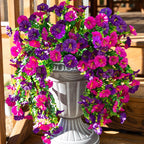 Decorative floral arch with pink and purple flowers in front of a stone urn.