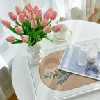 Pink tulips in a vase on a coffee table with a magazine and candle