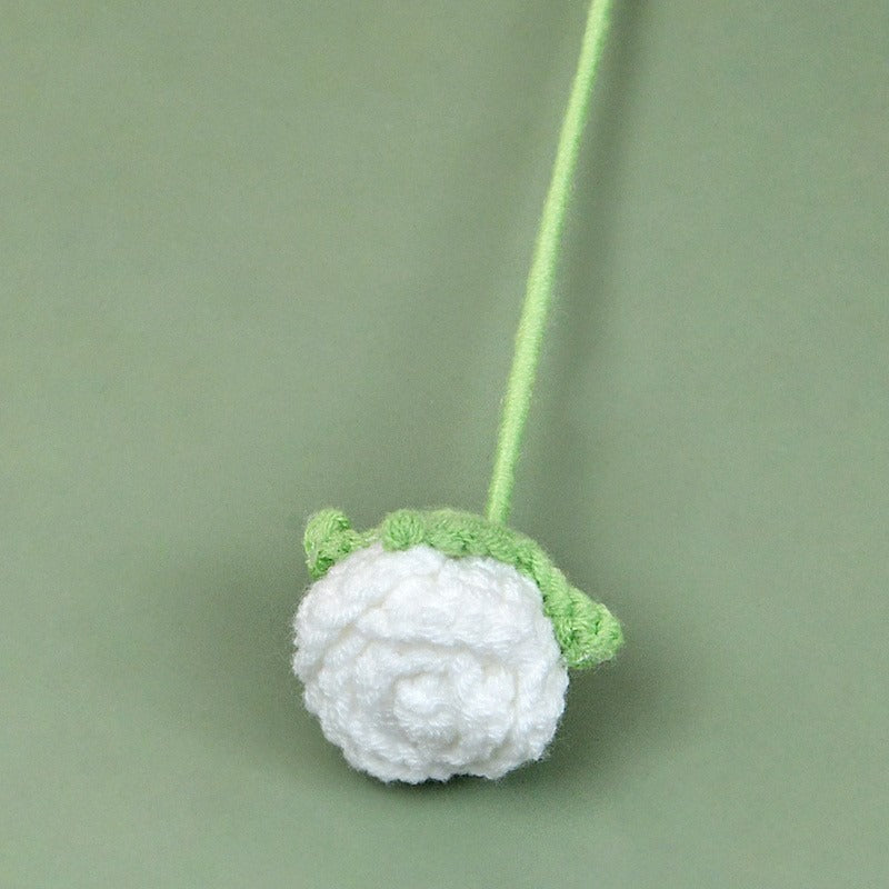 Crocheted white flower with green leaves on a green background