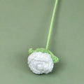 Crocheted white flower with green leaves on a green background