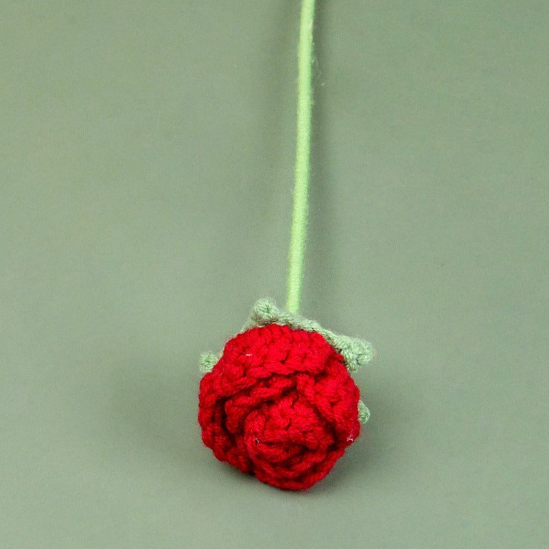 Crocheted red rose on a green background