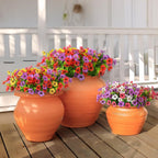 Three terracotta pots with colorful flowers on a wooden deck.