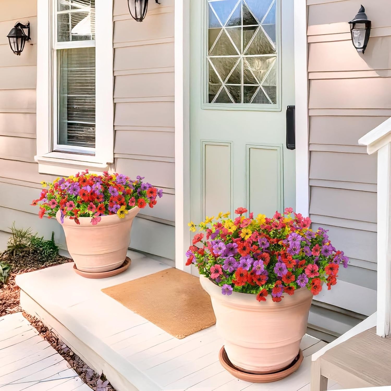 Two flower pots with colorful flowers on a porch with a light blue door.