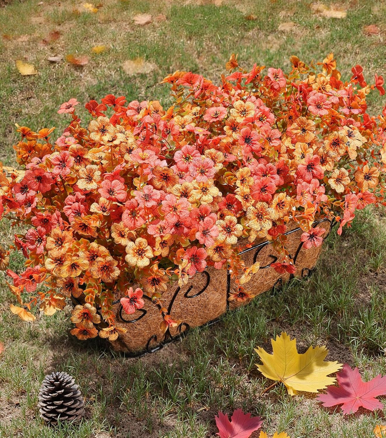 Decorative wheelbarrow filled with autumn-themed flowers on a grassy background.