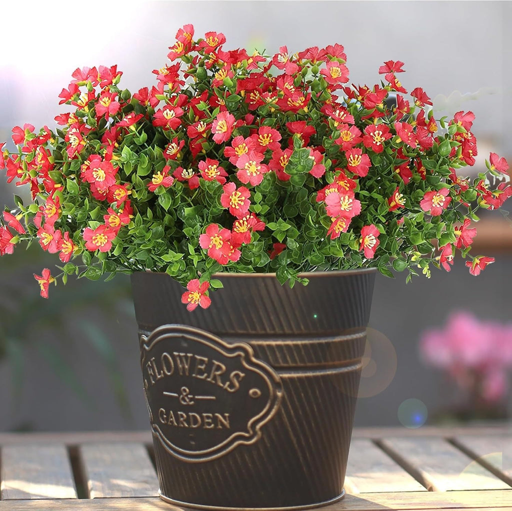 Potted plant with red flowers in a decorative pot on a wooden surface