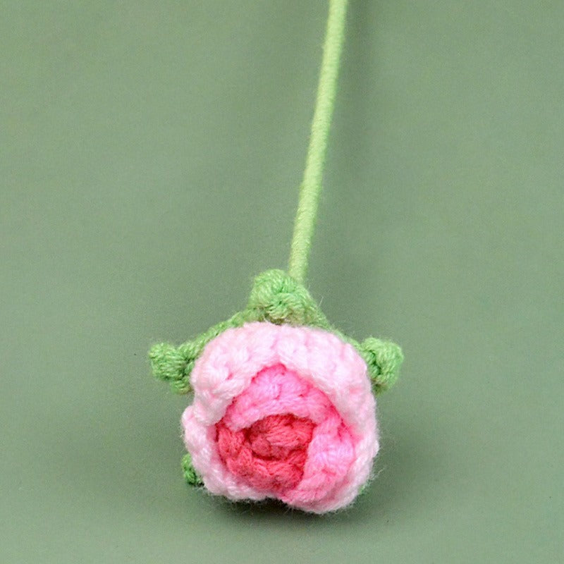 Crocheted pink rose on a green background