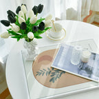 Round white table with a vase of black and white tulips, a cup and saucer, and a magazine.