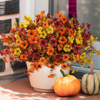 Autumn-themed floral arrangement with pumpkins on a porch.