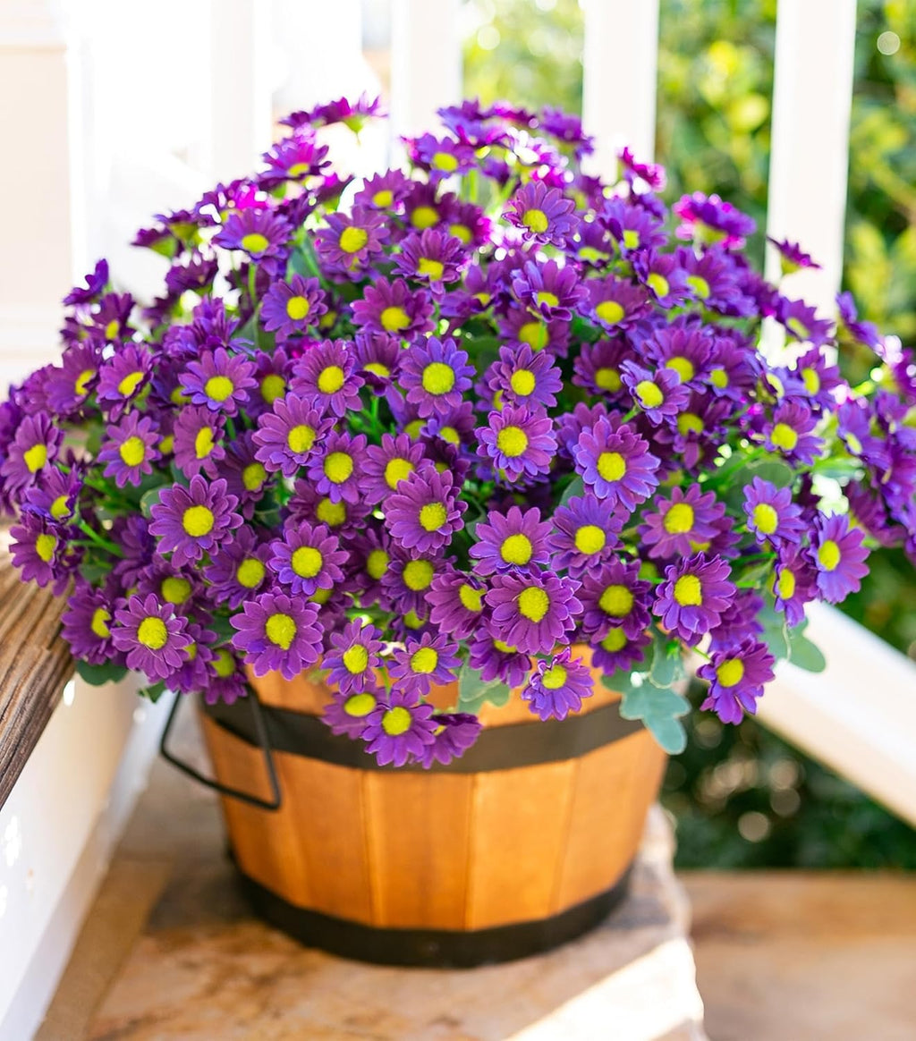 Potted purple flowers with yellow centers in a wooden basket on a wooden surface.