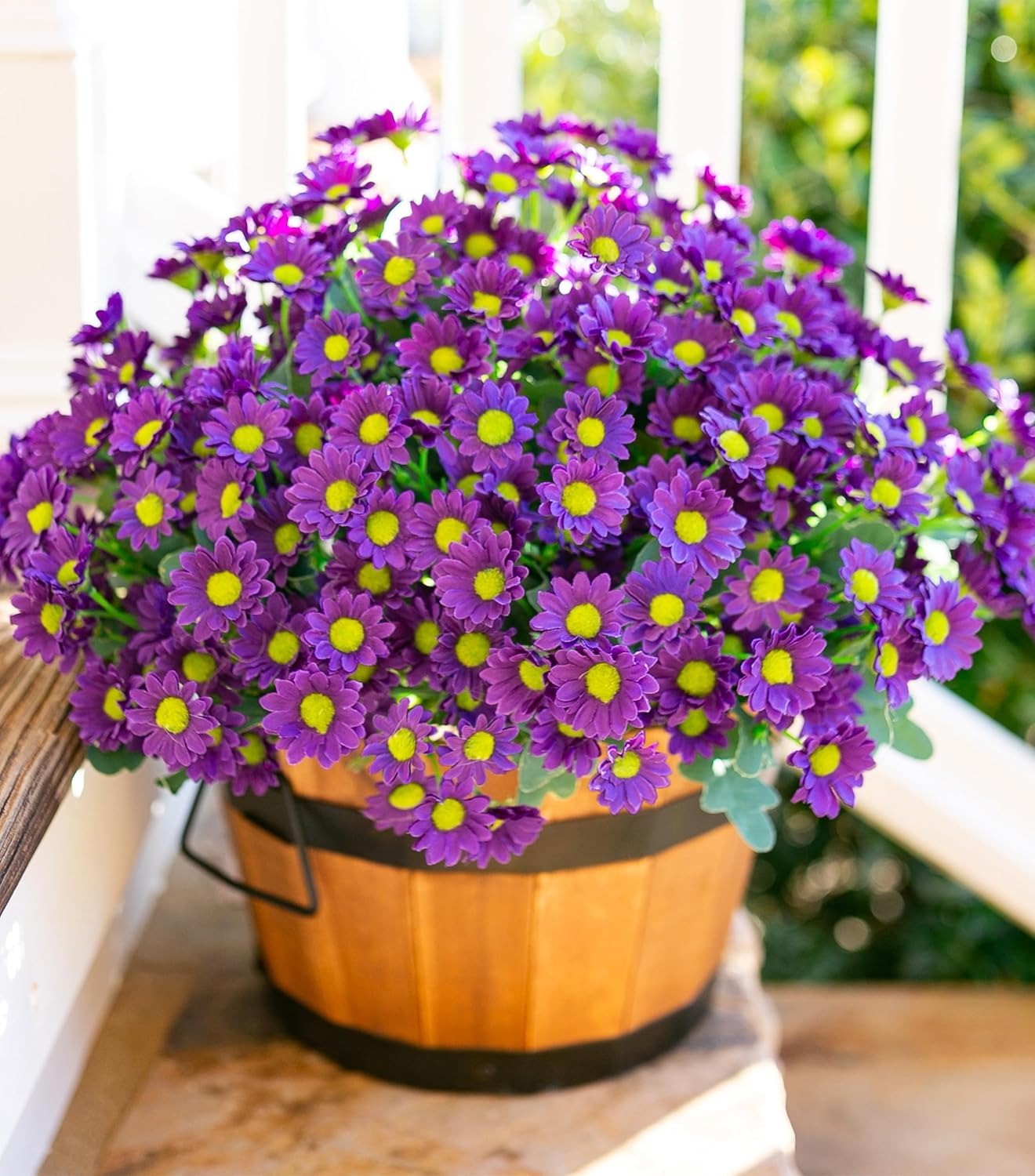 Potted purple flowers with yellow centers in a wooden basket on a wooden surface.