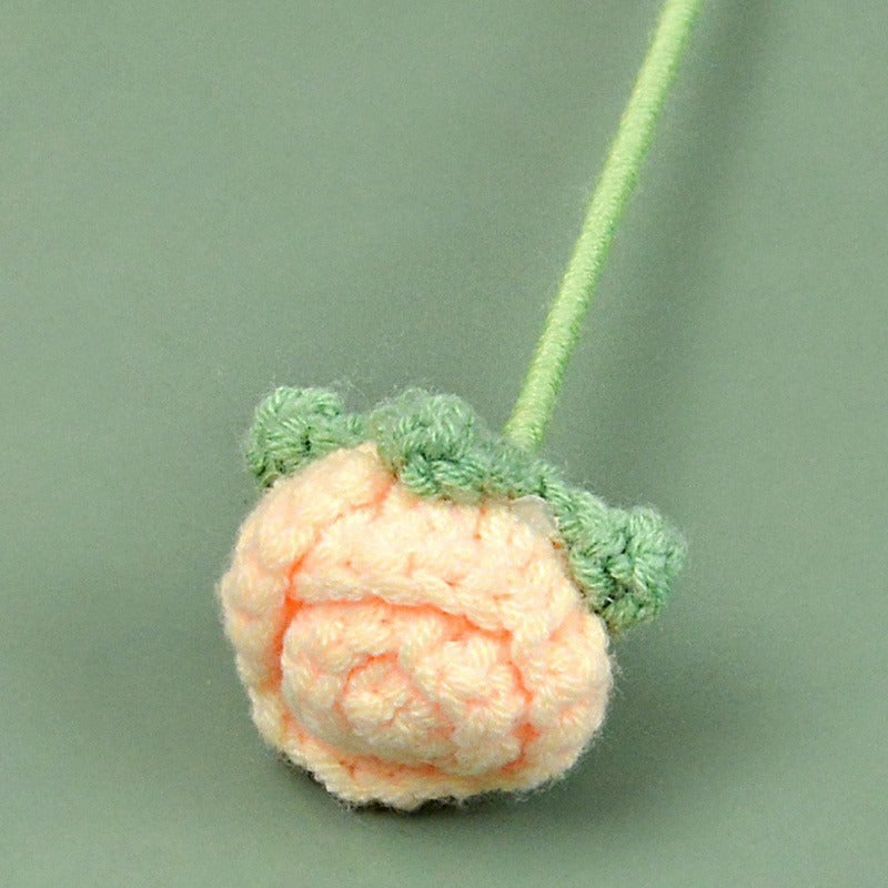 Crocheted peach-shaped object with green stem on a light green background