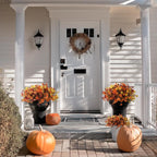 Front door with wreath, pumpkins, and flowers on a porch
