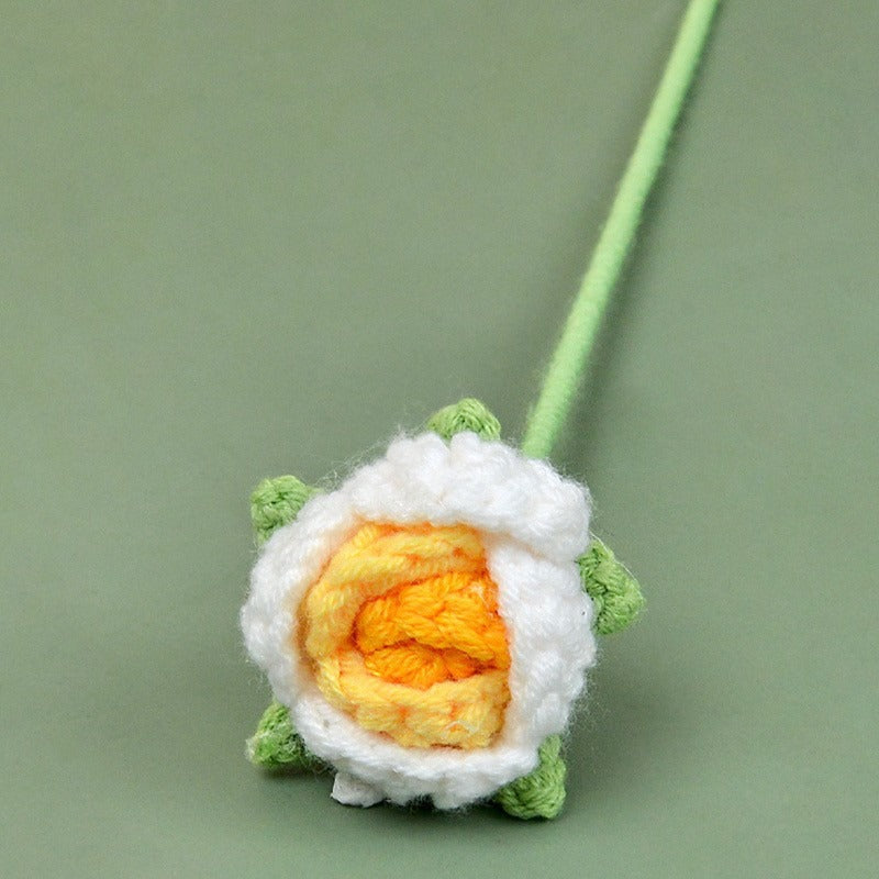 Crocheted sushi roll toy with white rice, orange fish, and green seaweed on a green background