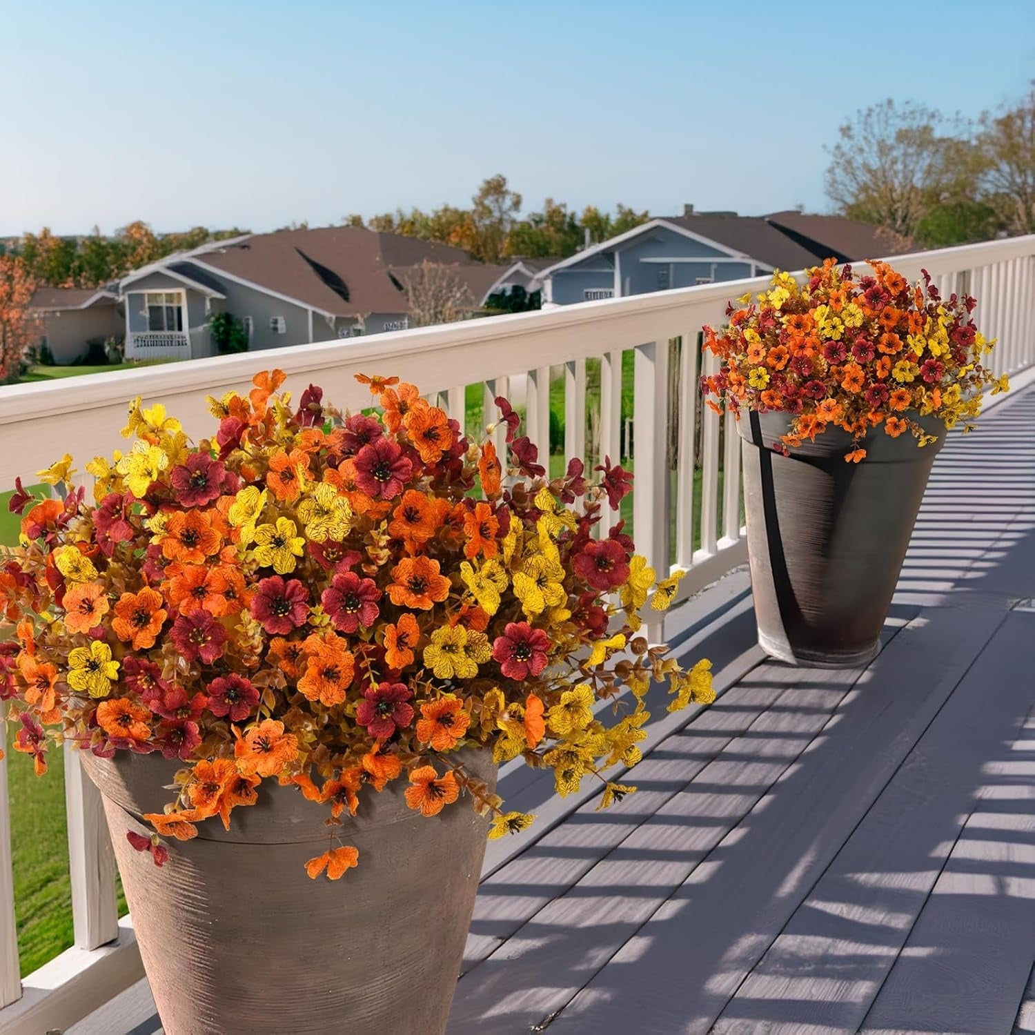 Two flower pots with colorful flowers on a wooden deck.