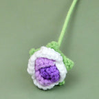Crocheted flower with green leaves on a light green background